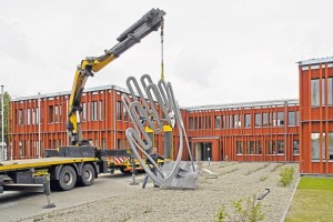 Über vier Meter hoch, mehr als drei Meter breit und knapp zwei Meter tief zieht die Eisenskulptur künftig die Blicke magisch auf sich. Das stahlgraue Kunstwerk wird sich durch Rosten in kurzer Zeit der Farbe der Holzfassade des Amtes für ländliche Entwicklung anpassen. Erst dann ist das Werk wirklich komplett fertig.